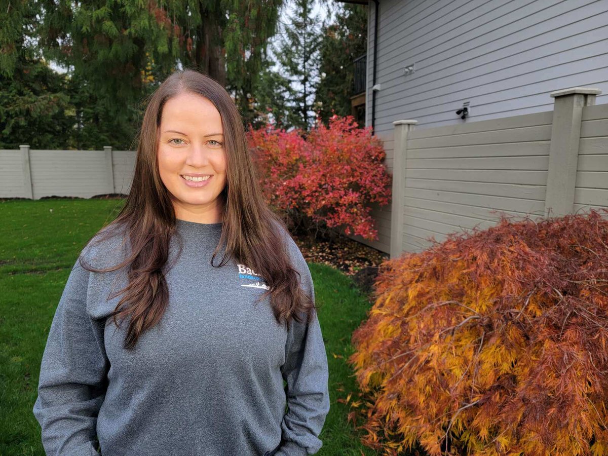 Natasha Maerz, co-owner of Back 40 Landscaping in Abbotsford, BC, posing in a landscaped backyard with fall foliage