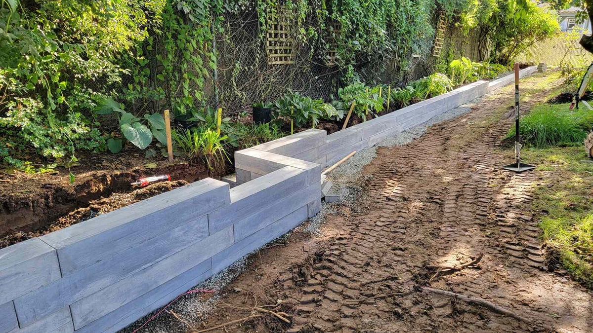 Completed section of wood-textured concrete retaining wall in landscaped yard by Back 40 Landscaping, Abbotsford, BC