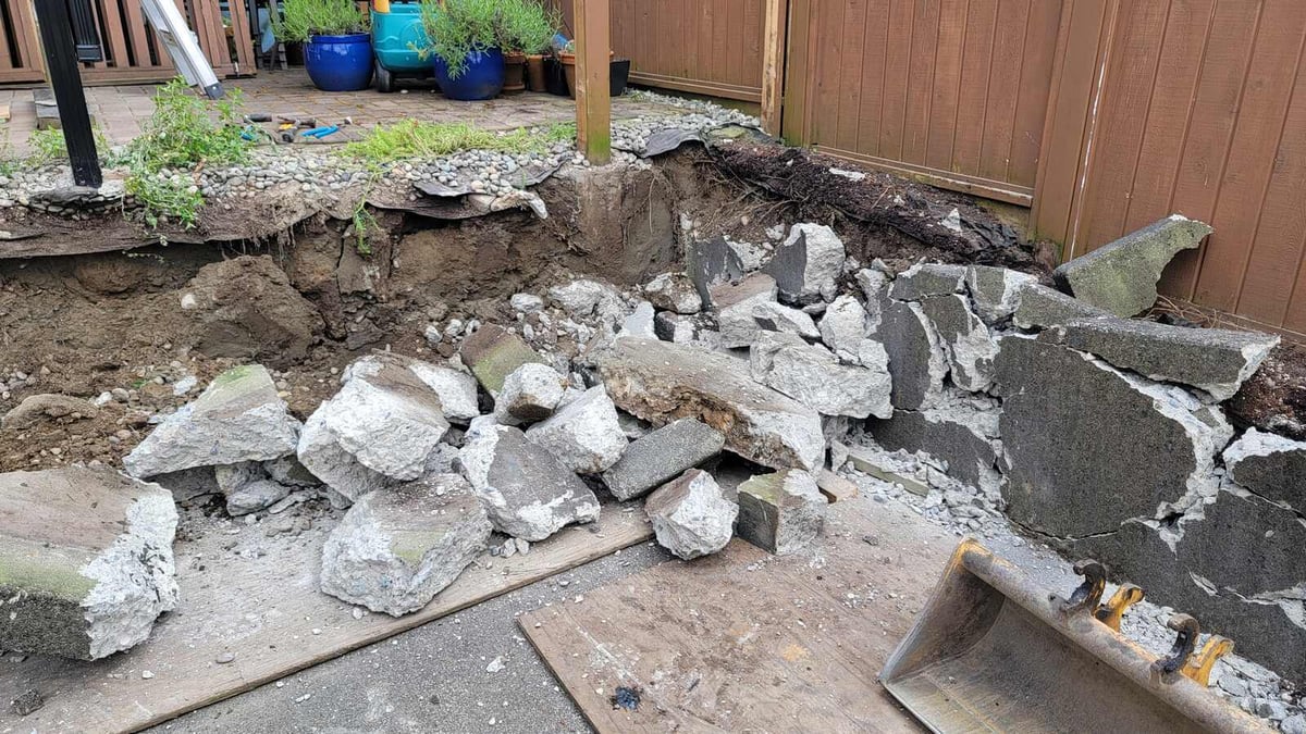 Retaining wall demolition in progress with broken concrete pieces, Langley, BC, by Back 40 Landscaping