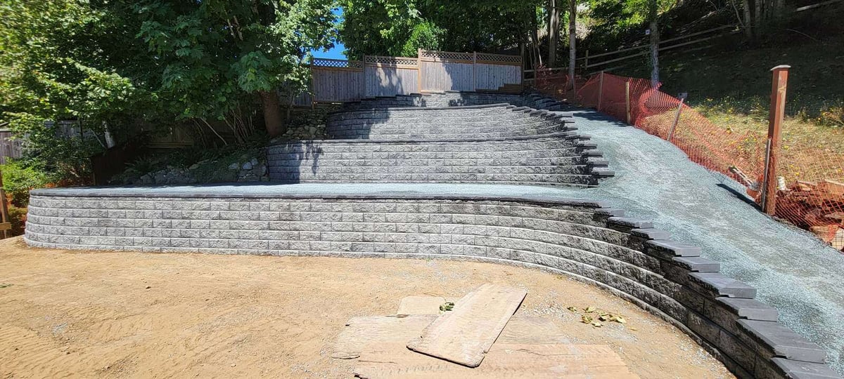 Side view of a completed four-tier retaining wall in Langley, BC, landscaped by Back 40 Landscaping