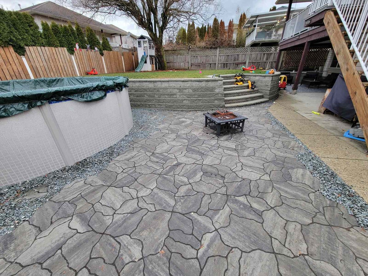 Patio area with flagstone pavers and above-ground pool setup by Back 40 Landscaping in Mission, BC